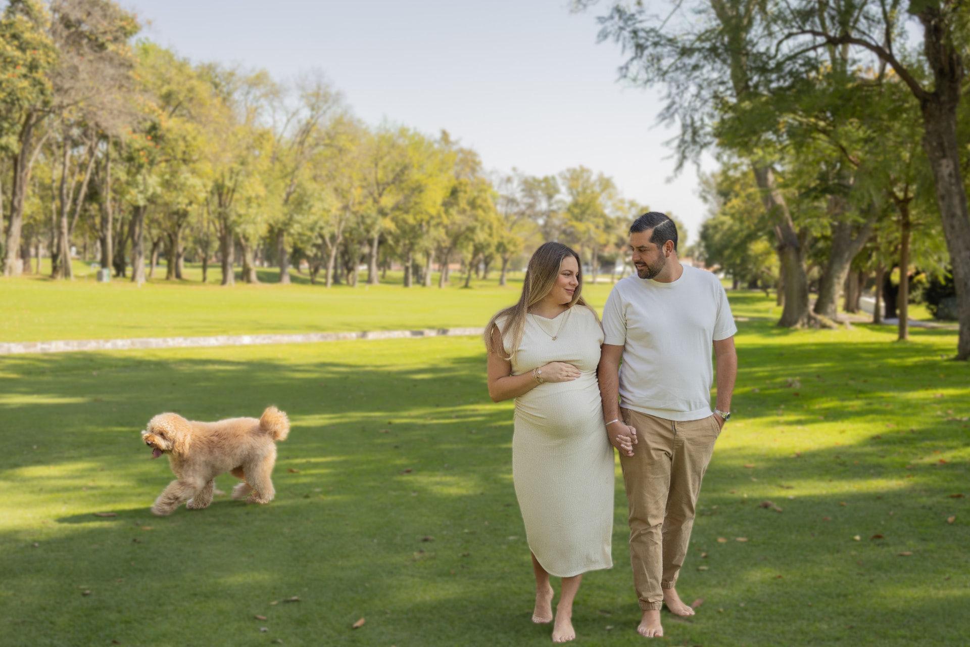 Futuros papás caminando juntos en un jardín con su perro